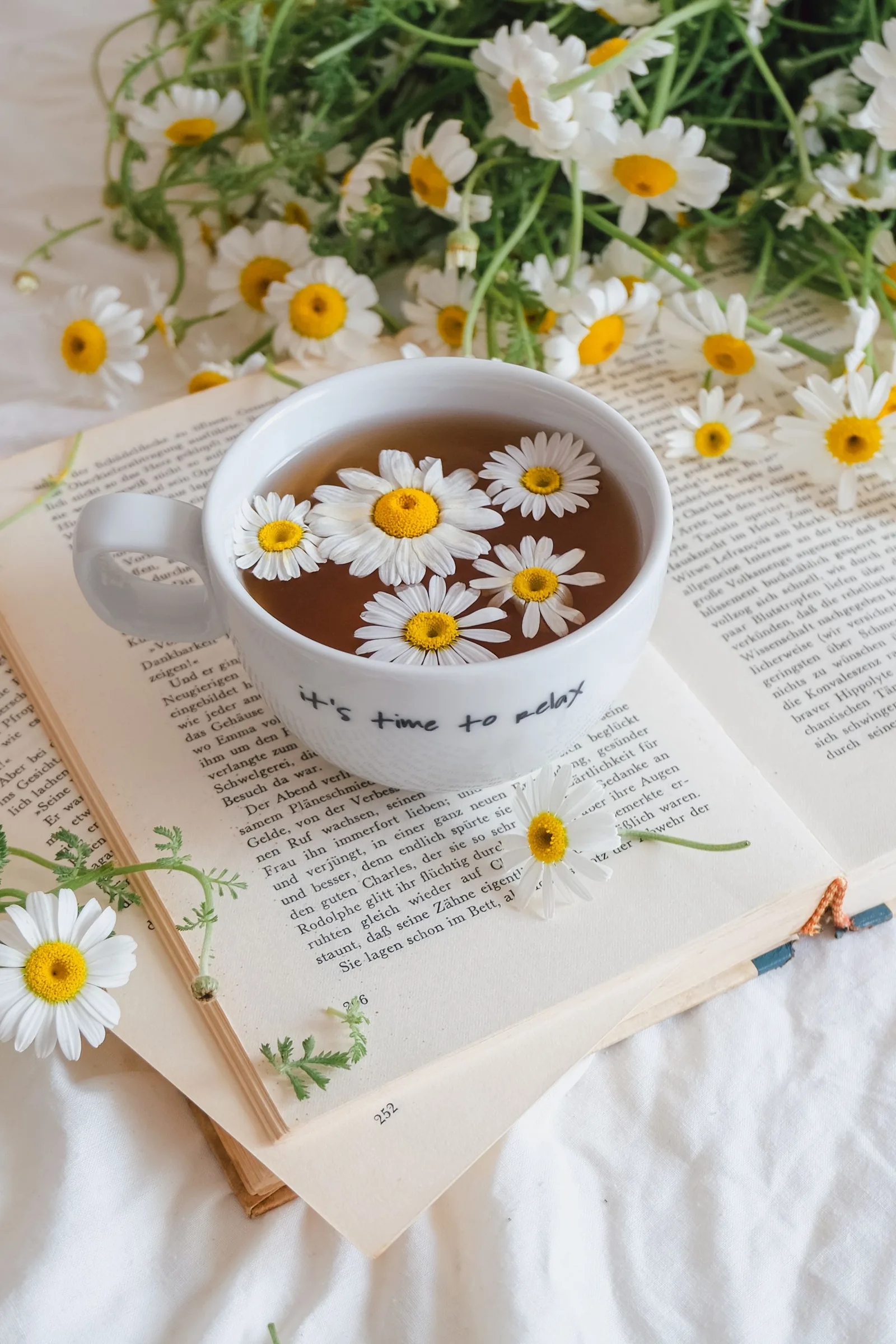 Tasse de tisane à la camomille posée sur un livre ouvert